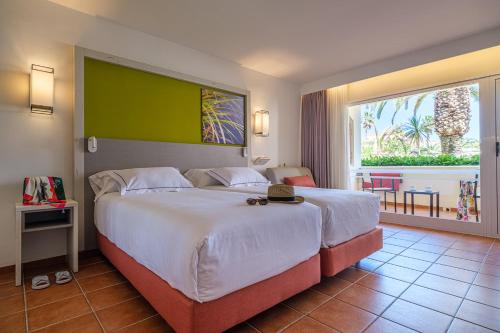 a bedroom with a large bed and a large window at Oassium Hotel - Adults Only in La Pineda