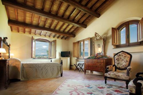 a bedroom with a bed and a chair and windows at Valle di Assisi Country Apartments in Assisi