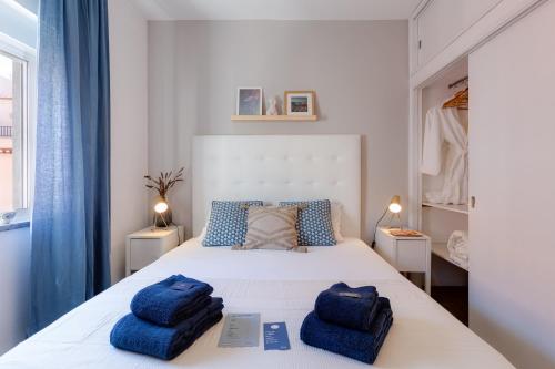 Un dormitorio con una cama blanca con toallas azules. en Indigo Guest House, en Lagos