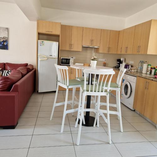 una cucina con tavolo, sedie e frigorifero di PERNERA 33 Beach House a Protaras