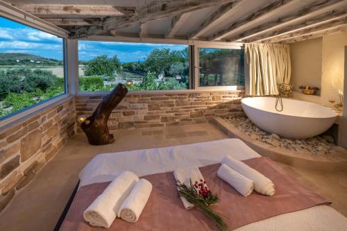 uma casa de banho com banheira e uma grande janela em K Bozcaada Revma em Bozcaada
