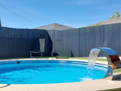 a swimming pool with a water fountain at Casa con piscina climatizada y barbacoa in Freigido