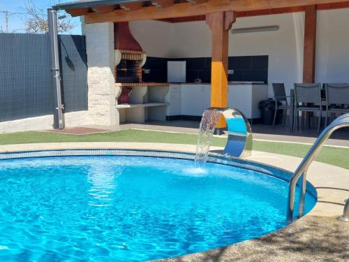 a swimming pool with a water fountain in a yard at Casa con piscina climatizada y barbacoa in Freigido