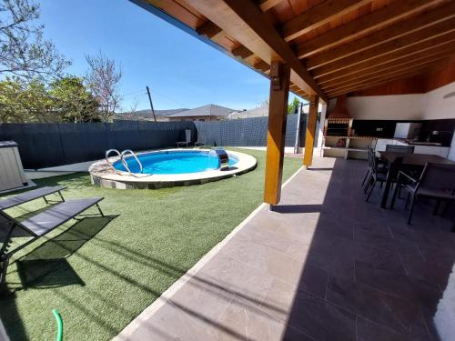 une terrasse avec une piscine, une table et des chaises dans l'établissement CASA CON PISCINA Y BARBACOA, à Freigido