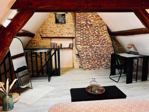 Cette chambre mansardée dispose d'un mur en briques et d'une table. dans l'établissement Le Cottage des Chalands, à Saint-Georges-sur-Cher