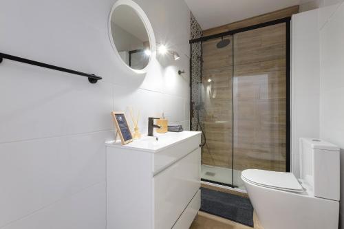 a white bathroom with a toilet and a mirror at Indigo Guest House in Lagos