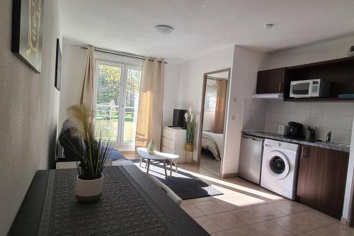 a living room with a kitchen with a washing machine at Appartement 10 MIN de Disneyland Paris in Montévrain