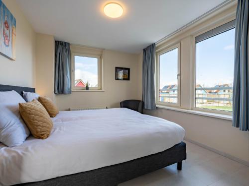 a bedroom with a large bed and two windows at Maxime 203 - Kustpark Village Scaldia in Hoofdplaat