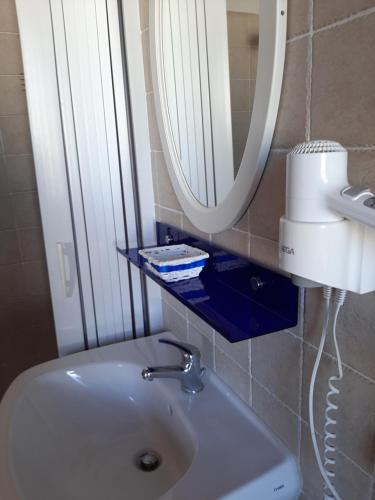 een badkamer met een witte wastafel en een spiegel bij B&B La Jacaranda affittacamere in SantʼAntìoco