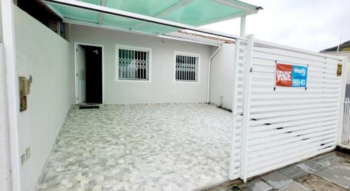 a white garage with a white fence and a door at Casa mobiliada recém reformada in Matinhos