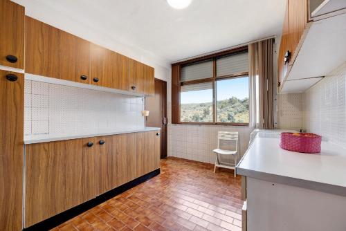 a kitchen with wooden cabinets and a window at Vila Portimão T5 com Piscina in Portimão