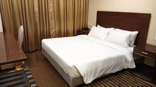 a bedroom with a large bed with white sheets and pillows at Layalee Grande Hotel Chennai in Chennai