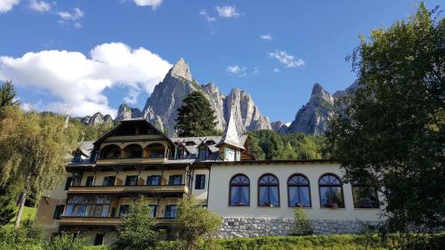a house in the mountains with mountains in the background at Hotel Salegg in Siusi