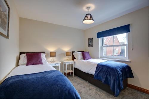 a bedroom with two beds and a window at Bakers Yard in Wells next the Sea