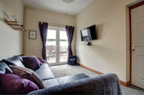 a living room with a couch and a tv at Bakers Yard in Wells next the Sea