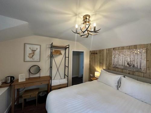Un dormitorio con una gran cama blanca y una lámpara de araña. en The New Forest Inn, en Lyndhurst
