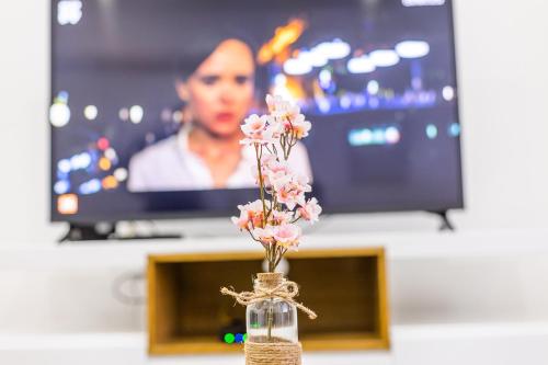 a vase with pink flowers in front of a tv at Prestígio Home in Alvito