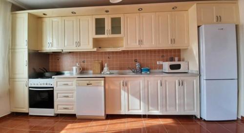 a kitchen with white cabinets and a white refrigerator at Apartments in Eşme