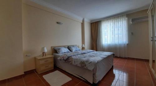 Schlafzimmer mit einem Bett, einem Nachttisch und einem Fenster in der Unterkunft Apartments in Eşme