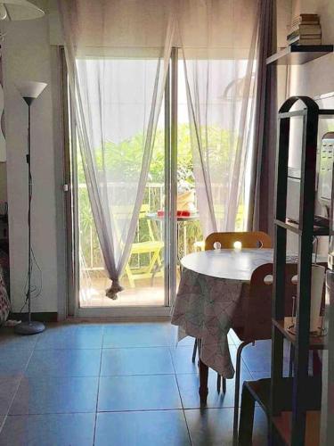 une salle à manger avec une table et une grande fenêtre dans l'établissement Studio avec jardinet et balcon idéalement situé, à Balaruc-les-Bains