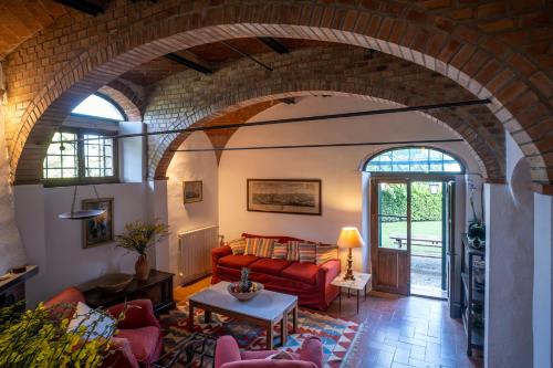 a living room with a red couch in a brick wall at Castello del Calcione in Lucignano