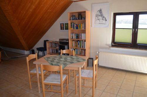 a dining room with a table and chairs and a book shelf at Gemütliche Dachgeschoßwohnung in Rheinbach
