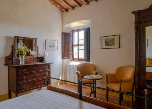 a bedroom with a dresser and two chairs and a mirror at Castello del Calcione in Lucignano