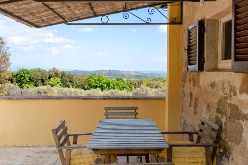 a wooden table and chairs on a balcony with a view at Castello del Calcione in Lucignano