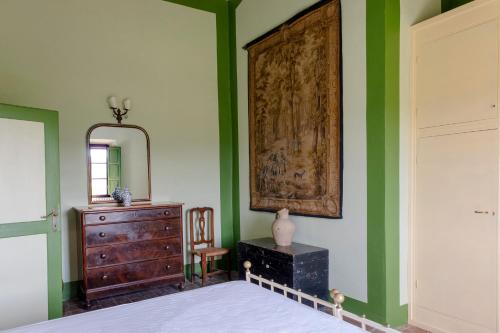 a bedroom with green walls and a dresser and a mirror at Castello del Calcione in Lucignano