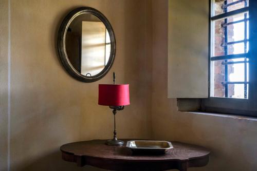 a table with a red lamp and a mirror at Castello del Calcione in Lucignano