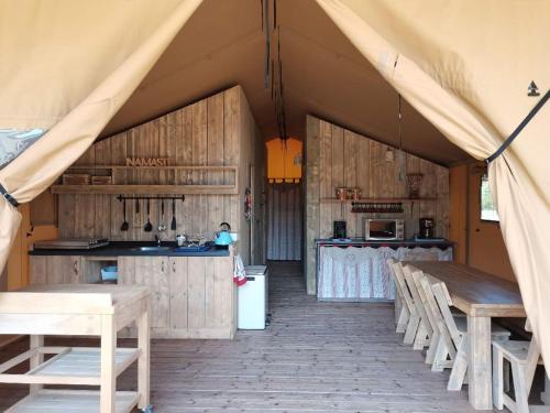 a tent with a kitchen and tables and chairs at Tente Lodge 13 couchages in Vaas