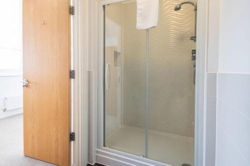 a shower with a glass door in a bathroom at Howells Mere 70, Sunnybank in Somerford Keynes