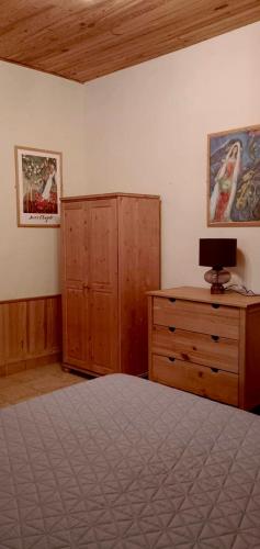ein Schlafzimmer mit einem Bett, einer Holzkommode und einem Schrank in der Unterkunft Petite maison au cœur du village in Nanteuil-en-Vallée