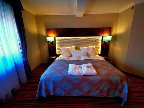 Una habitación de hotel con una cama con dos toallas. en The Lakeside - Burghotel zu Strausberg, en Strausberg