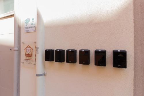 a row of black cell phones on a wall at Center Rooms in Piacenza