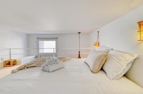 ein weißes Schlafzimmer mit einem großen weißen Bett und zwei Handtüchern in der Unterkunft L'Octopus - Petit patio estival in Marseille