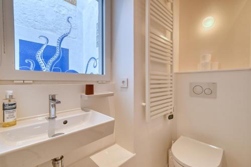 une salle de bain blanche avec un lavabo et des toilettes dans l'établissement L'Octopus - Petit patio estival, à Marseille