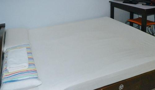 a bed with white sheets and a striped pillow on it at RedDoorz @ Limelily Pension Inn General Santos City in General Santos