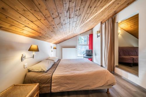 um quarto com uma cama grande e um tecto em madeira em Gîte Le Jorat - Appartement C em Bogève