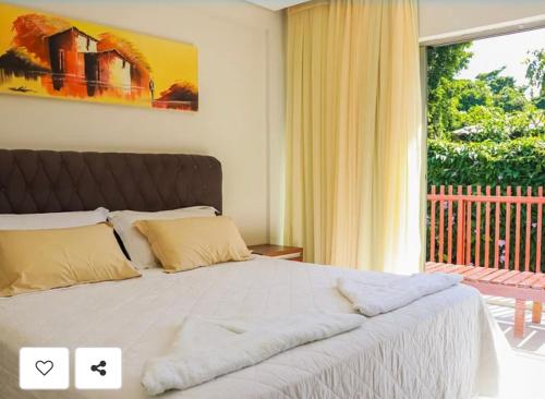 a bedroom with a bed with a large window at Flat Completo - Ilê de Pipa in Pipa