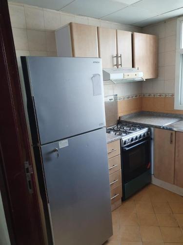 a kitchen with a white refrigerator and a stove at Marbella Holiday Homes - Al Nahda 1BHK in Dubai