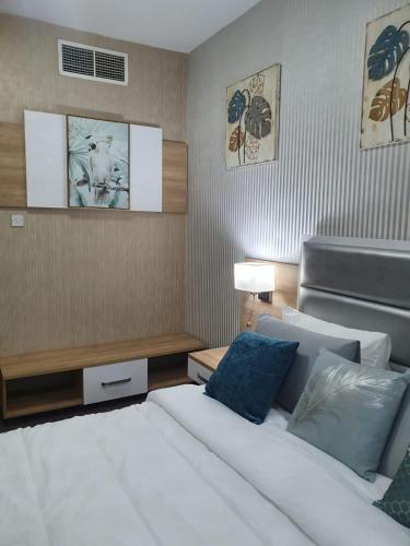 a bedroom with a white bed and blue pillows at Marbella Holiday Homes - Al Nahda 1BHK in Dubai