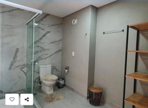 uma casa de banho com um WC e uma cabina de duche em vidro. em Flat Completo - Ilê de Pipa em Pipa