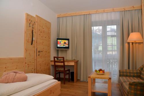 a hotel room with a bed and a desk and a television at Hotel Rauscher - Das Naturteichparadies in Bad Hofgastein
