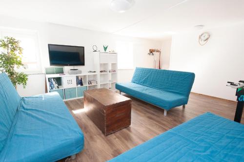a living room with two blue couches and a tv at Sailing House Piran in Piran
