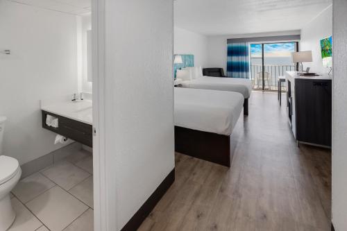 a hotel room with two beds and a sink and a toilet at Tropical Seas Hotel in Myrtle Beach