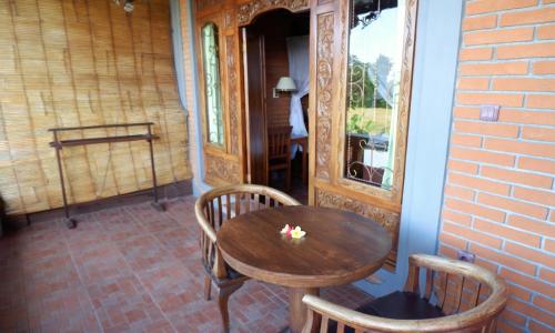 Danasari Homestay في أوبود: طاولة وكراسي خشبية على شرفة