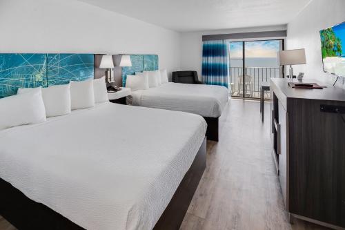 Tropical Seas Hotel في ميرتل بيتش: غرفة فندقية بسريرين وبلكونة