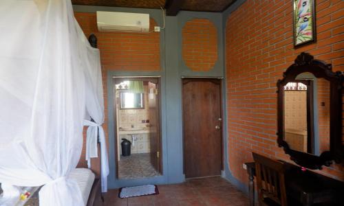 a room with a brick wall and a bedroom with a door at Danasari Homestay in Ubud