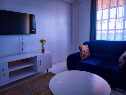 a living room with a blue couch and a tv at Cozier Domicile Apartments in Maragoli